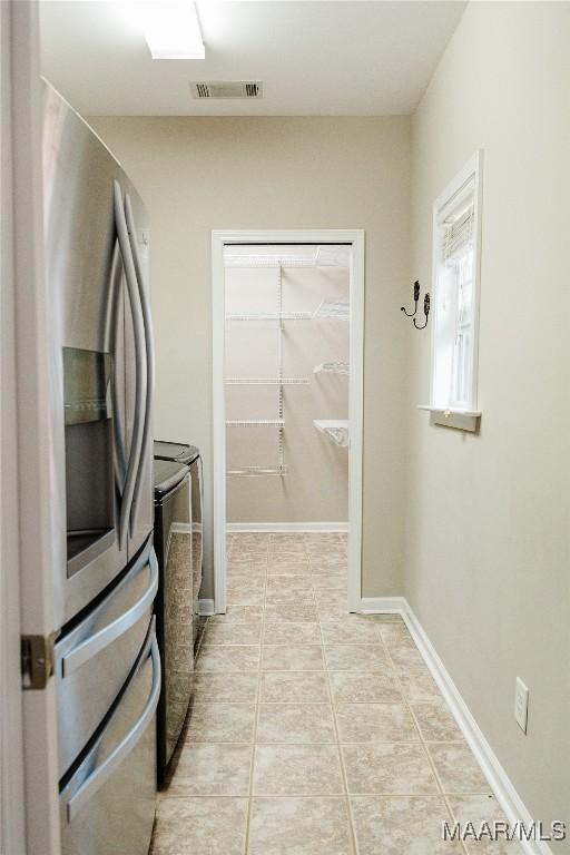 laundry area with independent washer and dryer and light tile patterned floors