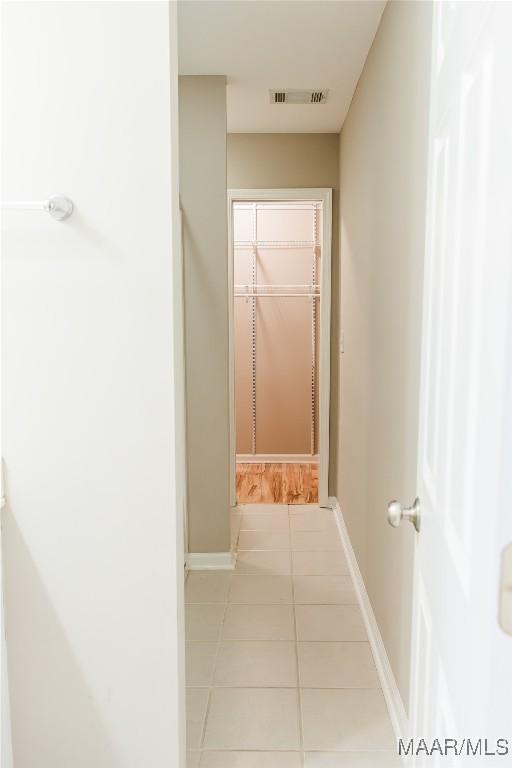 hallway with baseboards, visible vents, and tile patterned floors