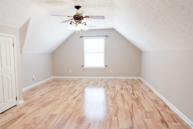 additional living space with lofted ceiling, ceiling fan, a textured ceiling, and light wood-type flooring