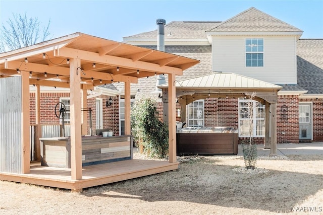 exterior space featuring brick siding, a hot tub, and a gazebo