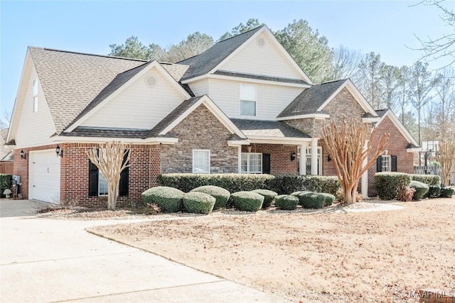 view of front of house with driveway, a garage, a shingled roof, stone siding, and brick siding