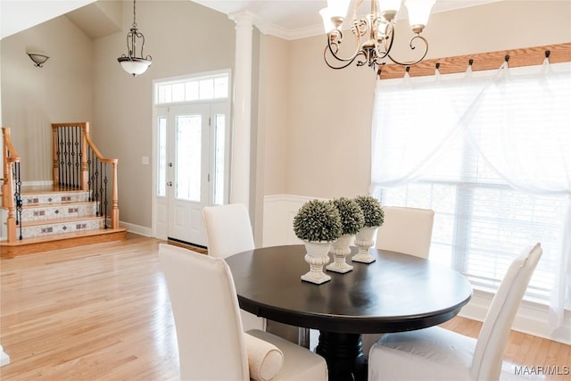 dining room featuring crown molding, hardwood / wood-style flooring, decorative columns, and a chandelier