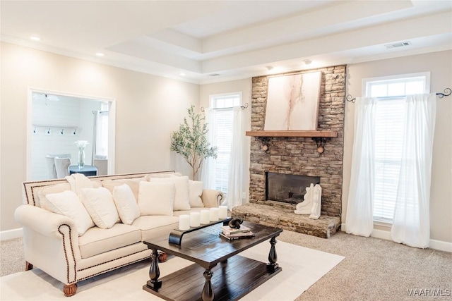 carpeted living room featuring a fireplace, crown molding, a wealth of natural light, and a raised ceiling