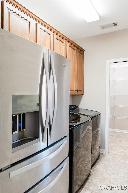 kitchen featuring separate washer and dryer, stainless steel fridge with ice dispenser, and light tile patterned floors