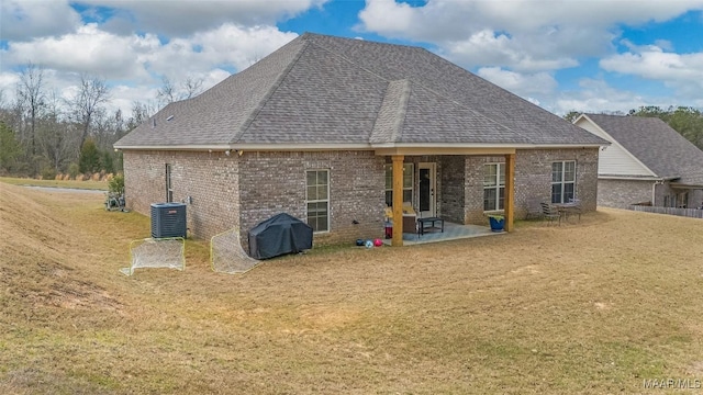 rear view of house featuring a patio, roof with shingles, a yard, central AC, and brick siding