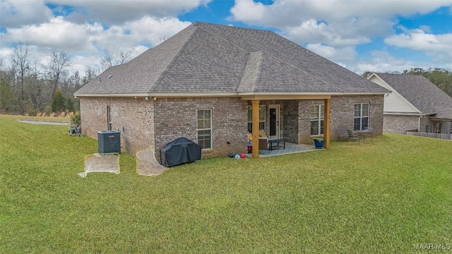 back of house featuring brick siding, a shingled roof, a lawn, and a patio