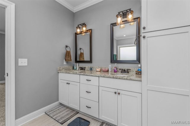 bathroom featuring ornamental molding, a sink, baseboards, and double vanity