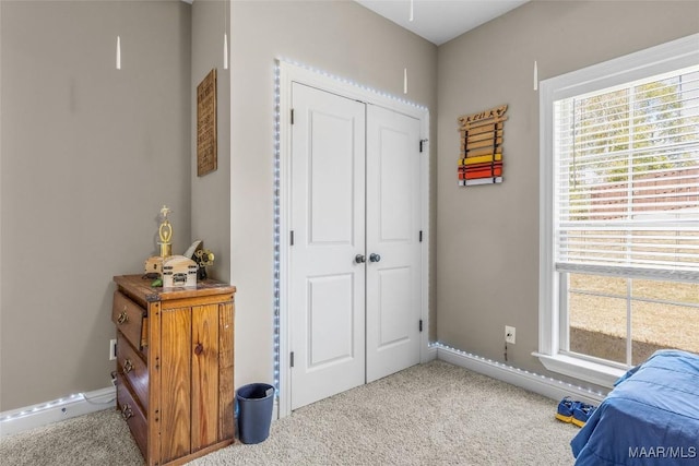 bedroom featuring carpet, multiple windows, baseboards, and a closet