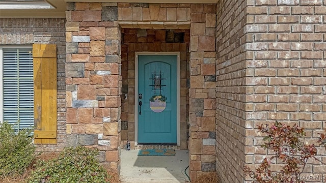 doorway to property featuring stone siding and brick siding