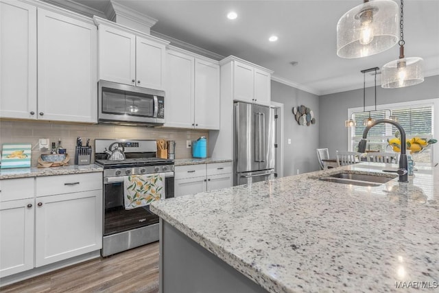 kitchen featuring crown molding, stainless steel appliances, backsplash, white cabinetry, and a sink