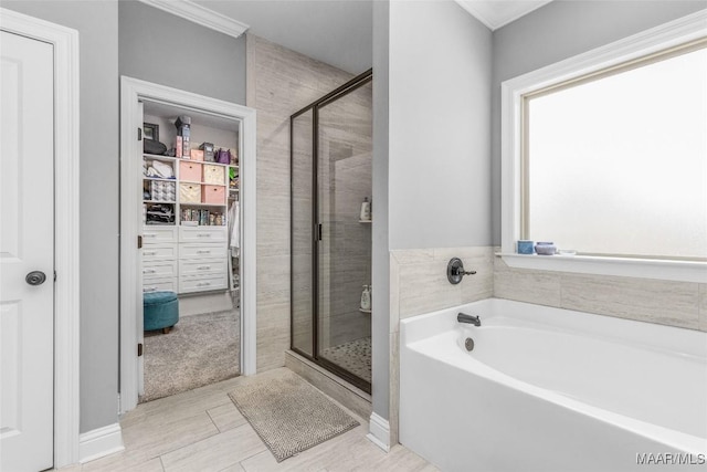 bathroom featuring a stall shower, a walk in closet, a garden tub, and crown molding