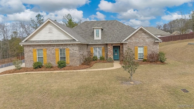 view of front of house featuring roof with shingles, fence, a front lawn, and brick siding