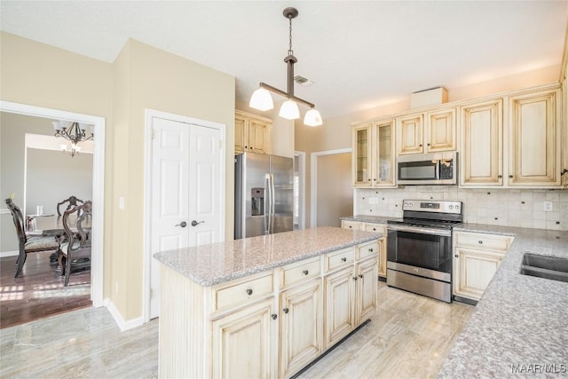 kitchen with decorative light fixtures, a center island, light hardwood / wood-style flooring, appliances with stainless steel finishes, and decorative backsplash