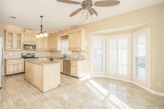 kitchen featuring sink, decorative light fixtures, a center island, appliances with stainless steel finishes, and backsplash