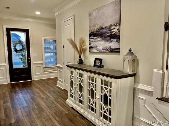 entryway with dark wood-type flooring and ornamental molding