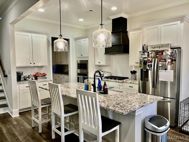 kitchen with stainless steel appliances, premium range hood, a kitchen island with sink, and white cabinets