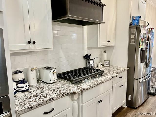 kitchen with white cabinetry, appliances with stainless steel finishes, and custom range hood