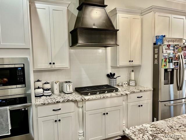 kitchen with backsplash, stainless steel appliances, custom range hood, and white cabinets