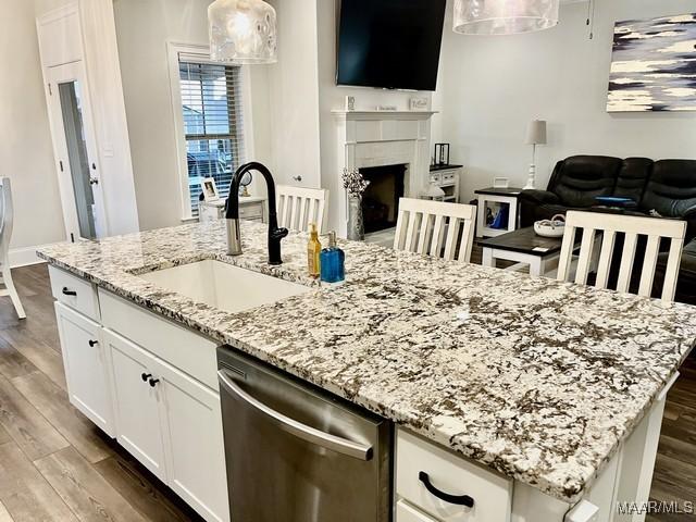 kitchen featuring white cabinetry, stainless steel dishwasher, sink, and an island with sink