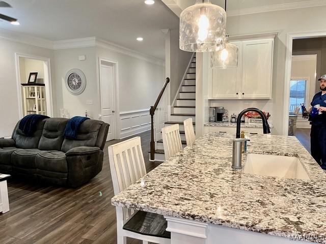 dining space with crown molding, sink, and dark wood-type flooring