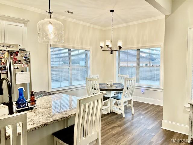 dining area featuring crown molding, dark hardwood / wood-style floors, and an inviting chandelier