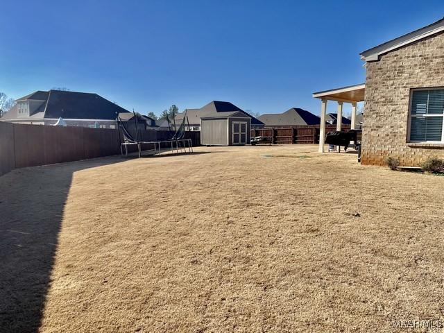 view of yard featuring a storage shed and a trampoline