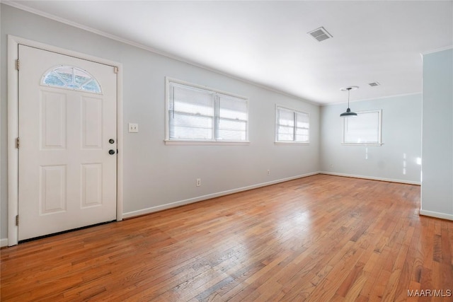 foyer entrance with ornamental molding and light hardwood / wood-style floors