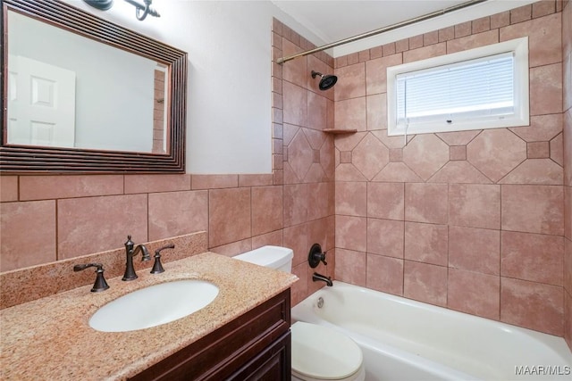 full bathroom with tiled shower / bath combo, vanity, tile walls, and toilet