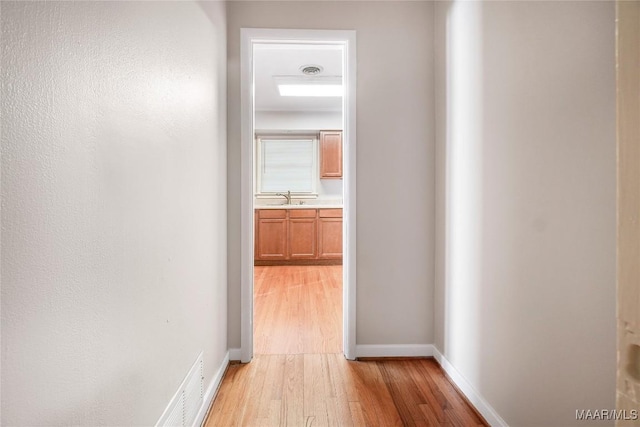 corridor with sink and light hardwood / wood-style floors