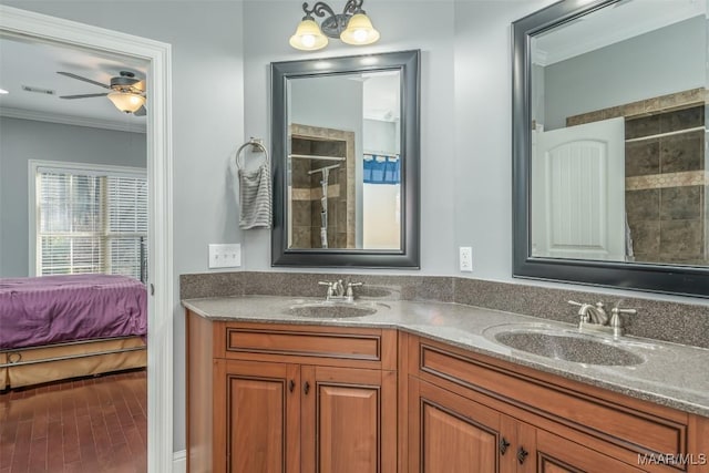 bathroom with crown molding, vanity, ceiling fan with notable chandelier, and a shower