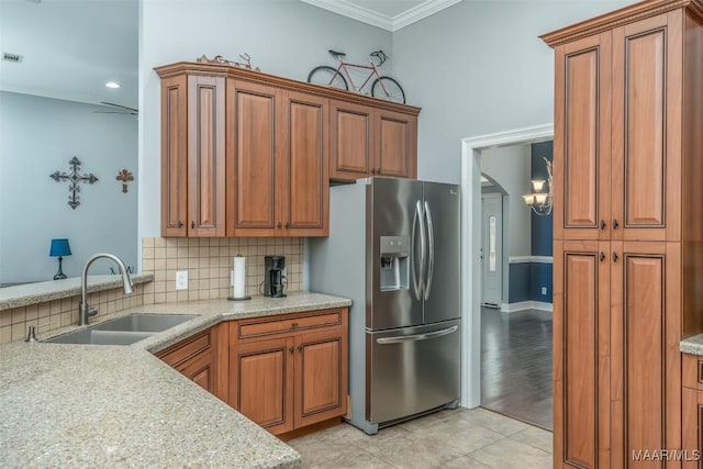 kitchen featuring tasteful backsplash, sink, crown molding, light stone counters, and stainless steel refrigerator with ice dispenser