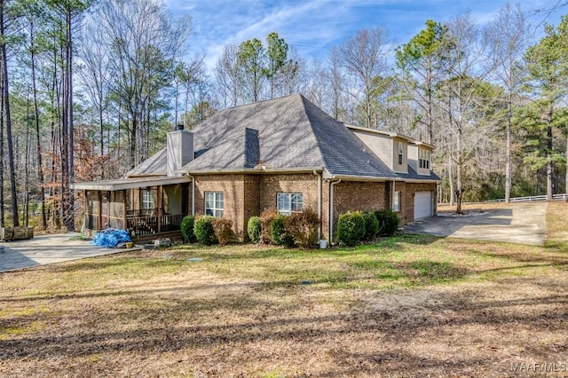 view of side of property with a garage, covered porch, and a lawn