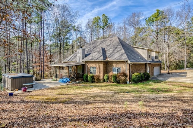 exterior space with a garage, a hot tub, a yard, and a sunroom