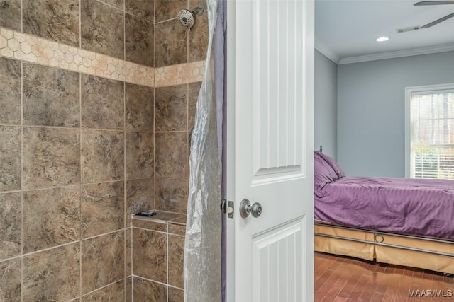 bathroom featuring hardwood / wood-style flooring, crown molding, and tiled shower