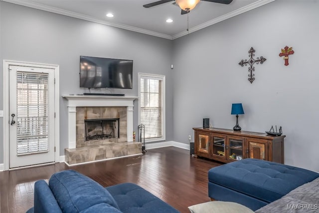 living room featuring dark hardwood / wood-style flooring, crown molding, a tile fireplace, and ceiling fan