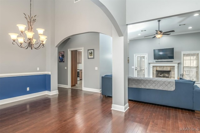 unfurnished living room with ceiling fan, dark wood-type flooring, a fireplace, and a towering ceiling