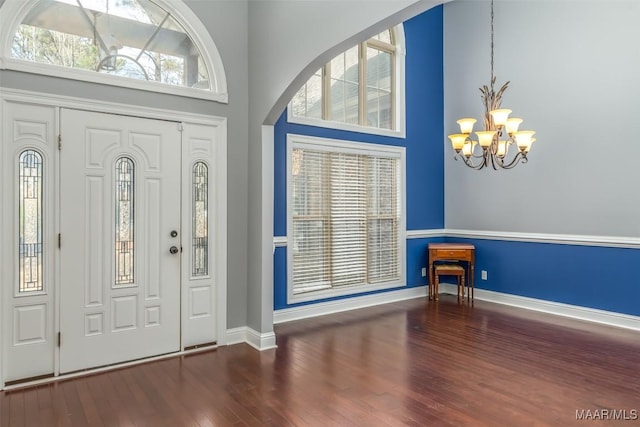 foyer with dark wood-type flooring, a towering ceiling, and a chandelier