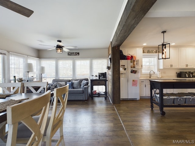 interior space with pendant lighting, sink, dark hardwood / wood-style floors, white fridge with ice dispenser, and white cabinets