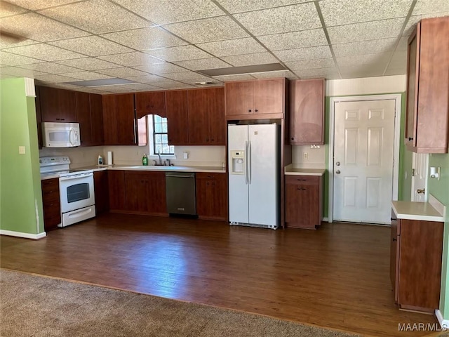 kitchen featuring white appliances, dark hardwood / wood-style flooring, a paneled ceiling, and sink