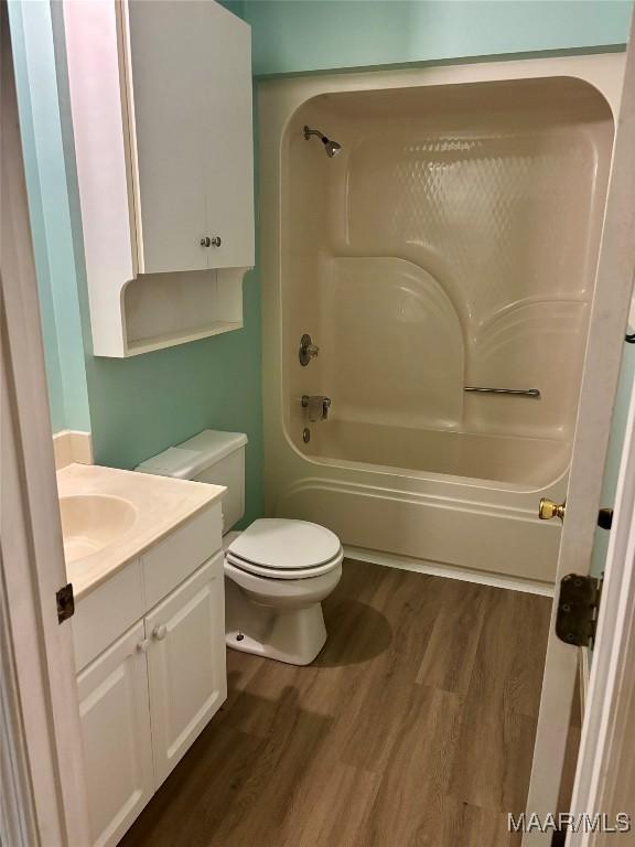 full bathroom featuring washtub / shower combination, wood-type flooring, toilet, and vanity