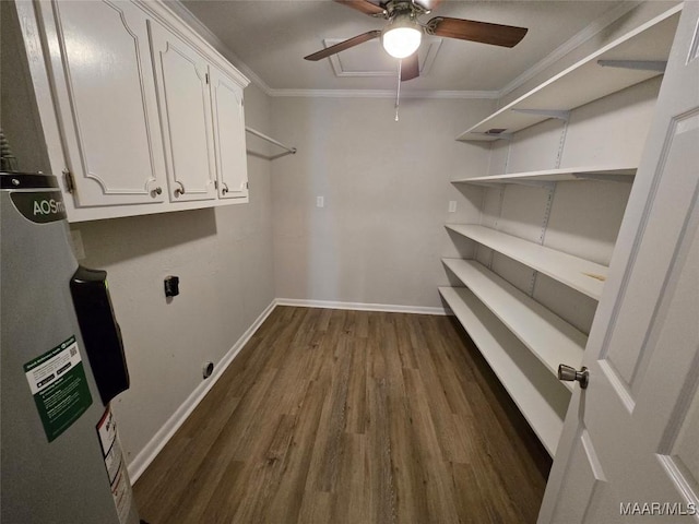 clothes washing area with cabinet space, dark wood finished floors, ornamental molding, electric water heater, and hookup for an electric dryer