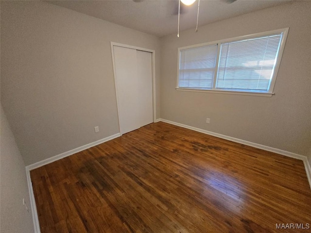 unfurnished bedroom featuring a closet, ceiling fan, baseboards, and wood finished floors