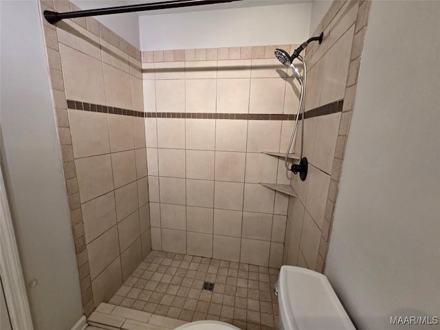 bathroom with a tile shower and toilet