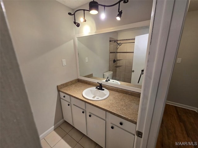 full bathroom featuring toilet, vanity, baseboards, tile patterned floors, and walk in shower