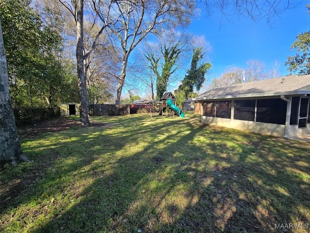 view of yard featuring a sunroom, a playground, and fence