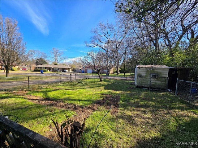 view of yard featuring fence, an outdoor structure, and a storage unit