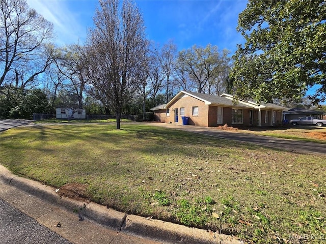 view of side of home with brick siding, a lawn, and fence