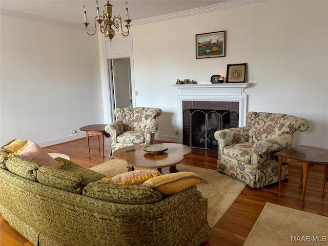 living room with ornamental molding, wood-type flooring, a fireplace, and a chandelier