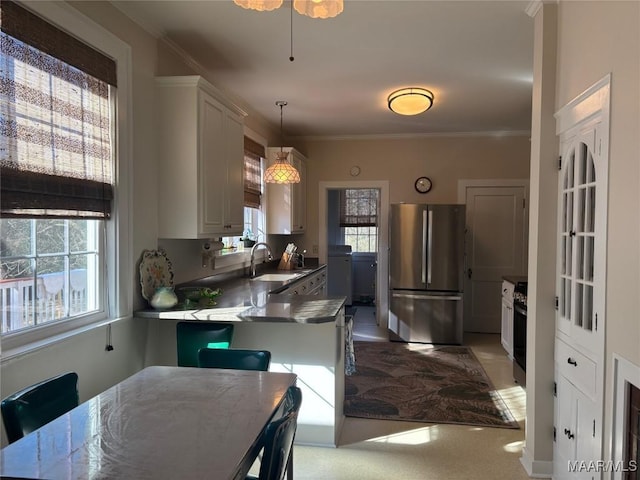 kitchen featuring sink, appliances with stainless steel finishes, white cabinetry, hanging light fixtures, and ornamental molding