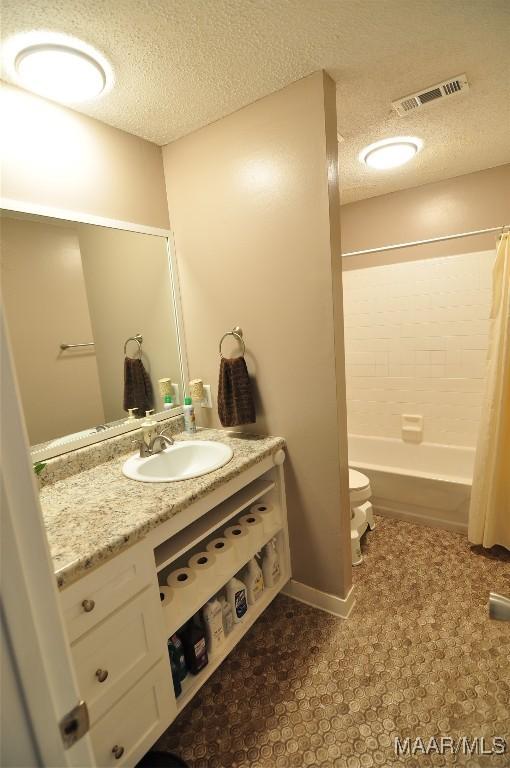 bathroom with vanity, shower / bathtub combination with curtain, and a textured ceiling